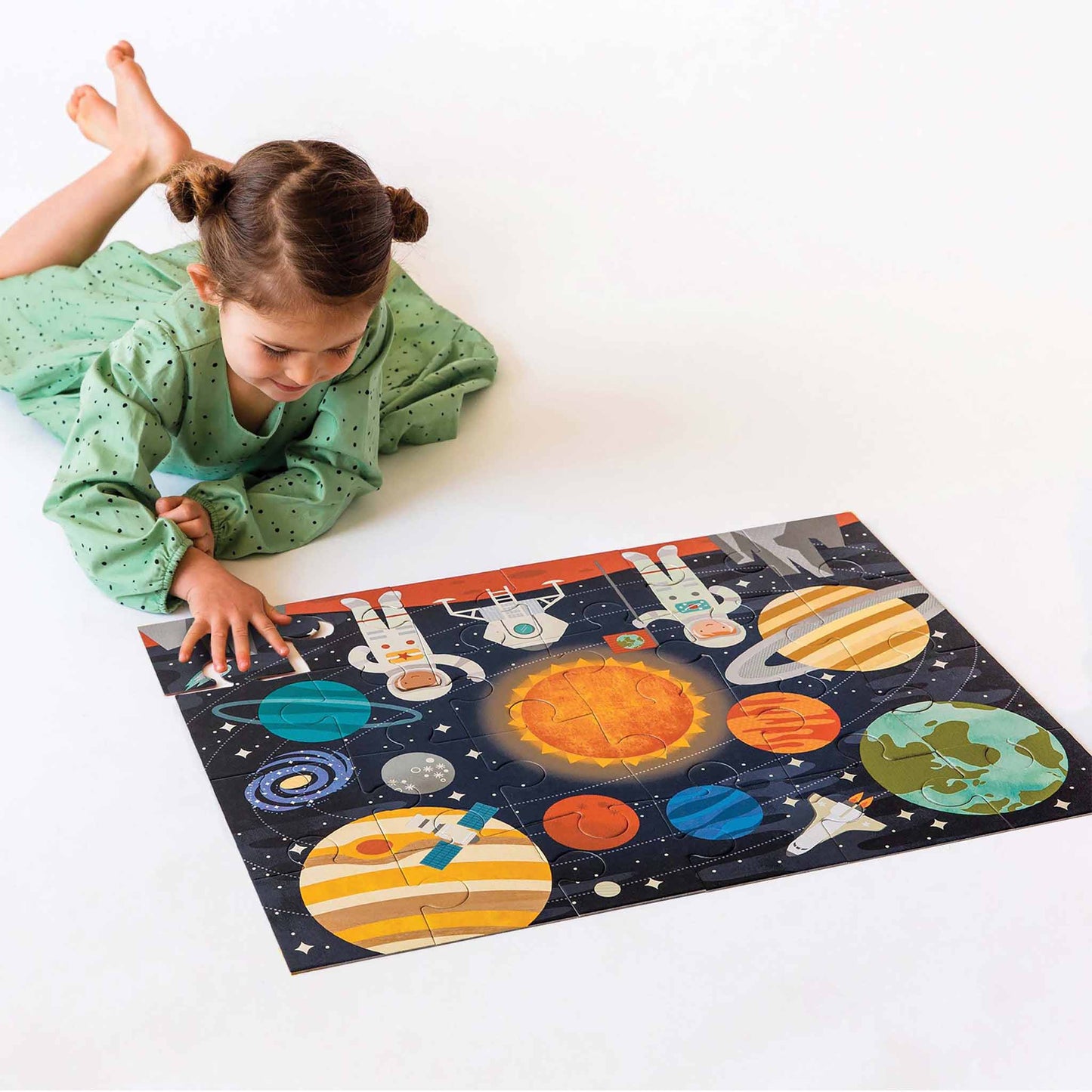 Child playing with a solar system puzzle on a white surface