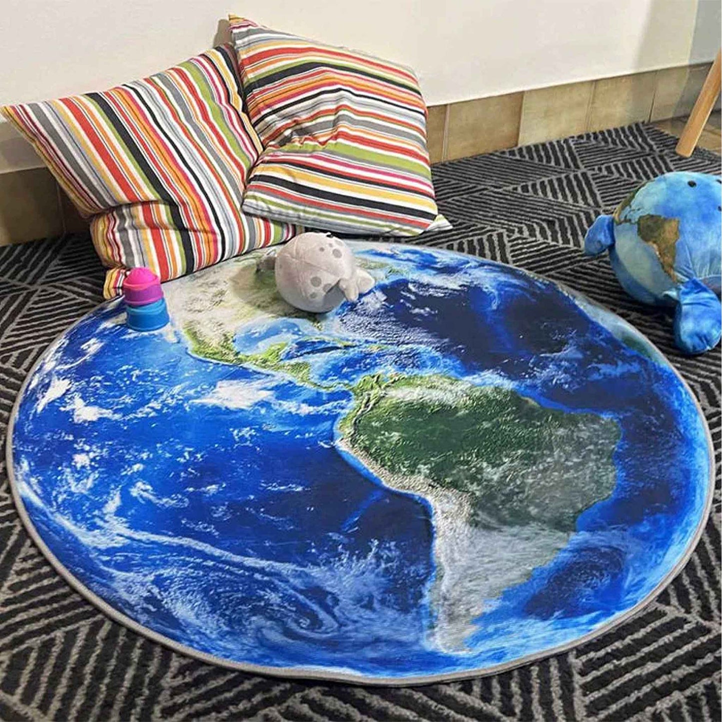 Round Earth-themed rug on a carpeted floor with colorful pillows in the background.