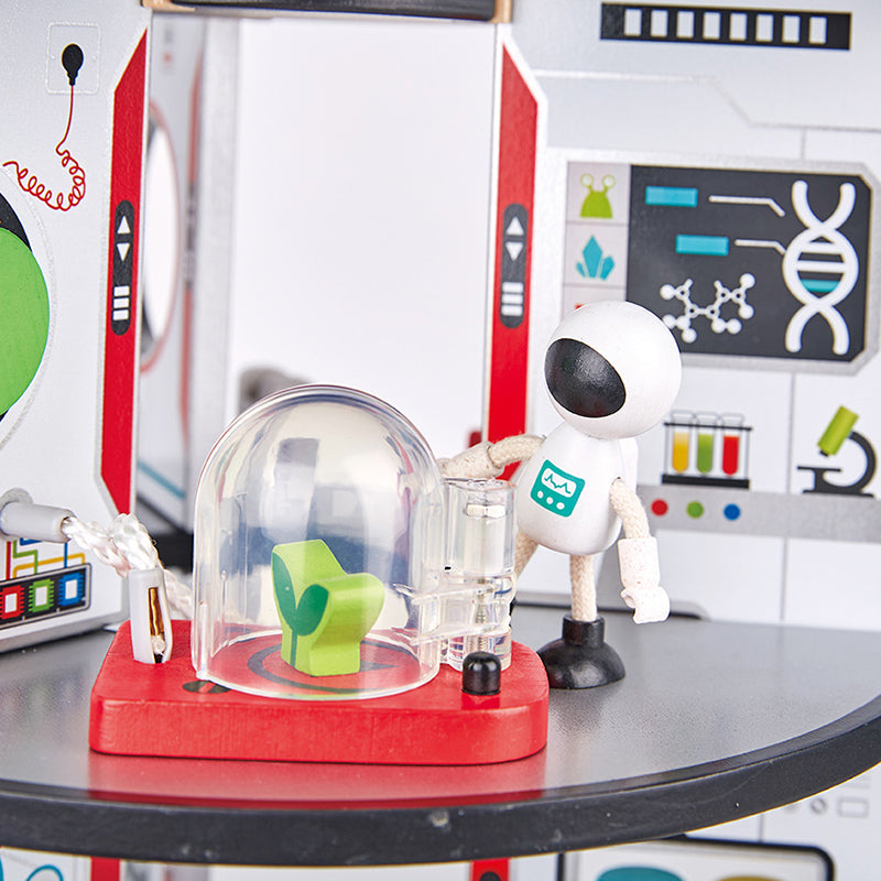 Toy robot interacting with a green chair inside a clear dome on a table.
