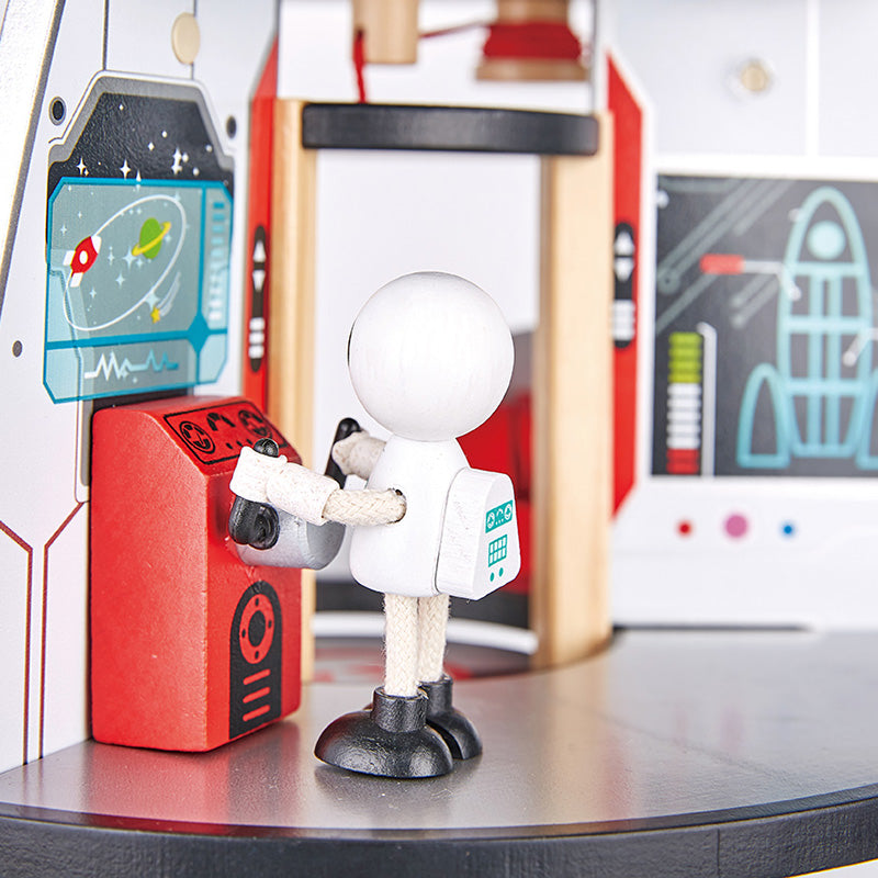 Small astronaut figurine interacting with a red control panel in a futuristic setting.