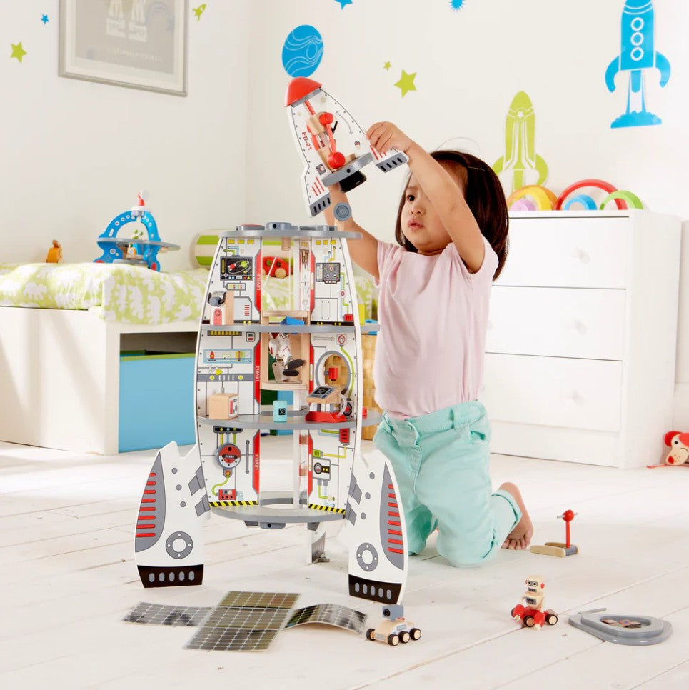 Child playing with a toy space shuttle in a room decorated with space-themed wall stickers.