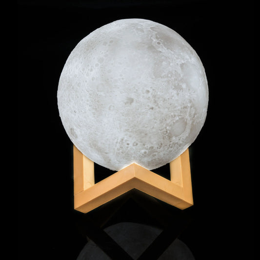 Moon-shaped lamp on a wooden stand against a black background