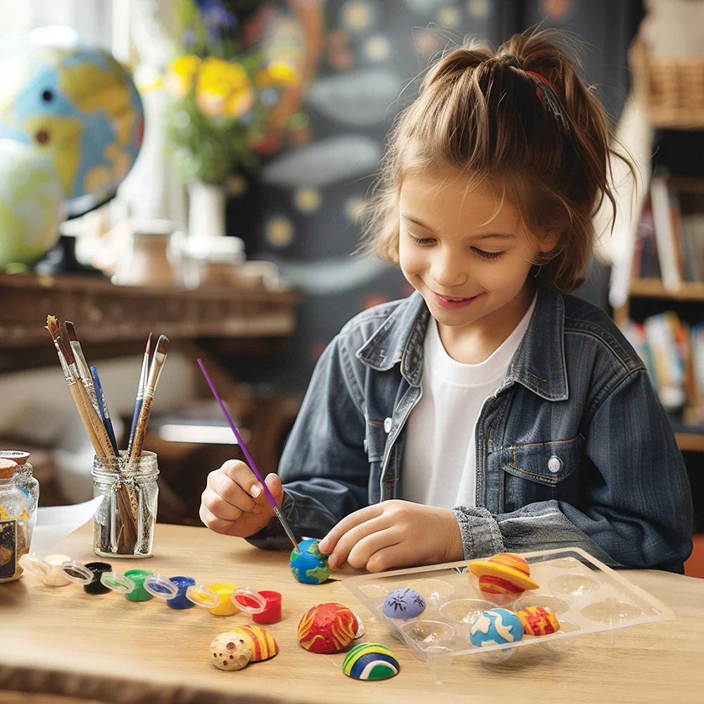 Child painting small figurines at a table with art supplies.