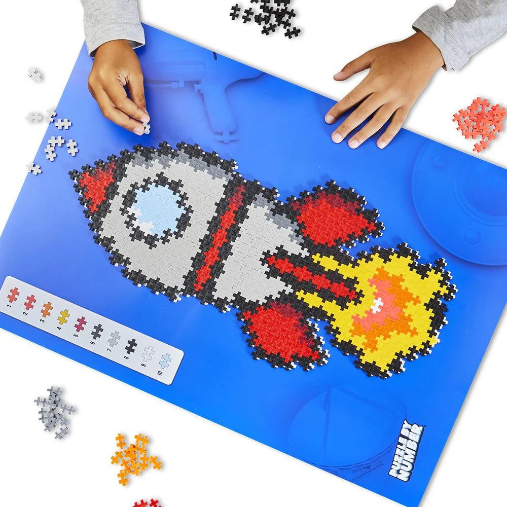 Children's hands working on a puzzle with a rocket design on a blue mat.