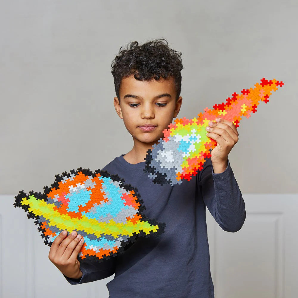 Child holding two colorful puzzle pieces shaped like planets against a plain background