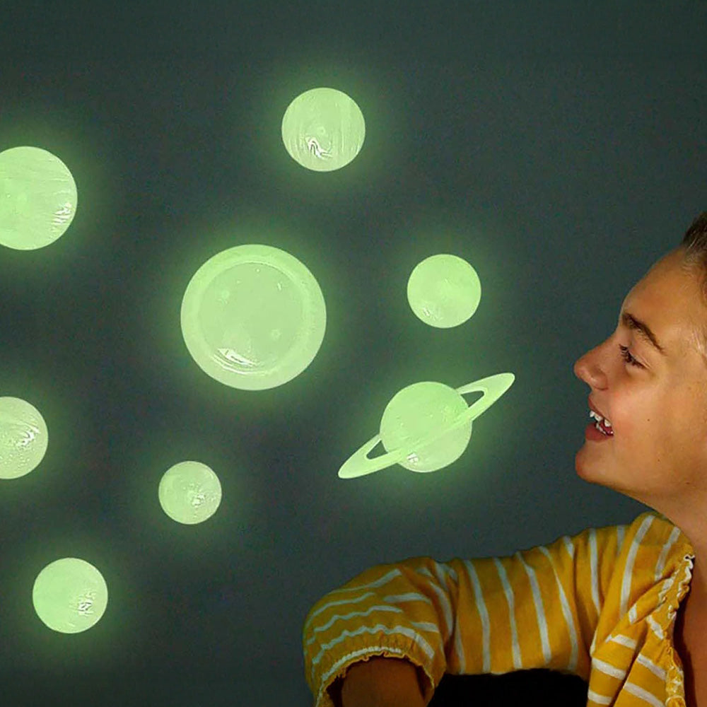 Child looking at glow-in-the-dark planet stickers on a dark wall