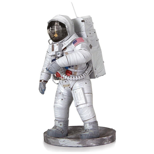 Statue of an astronaut in a white space suit with American flag patch on a white background