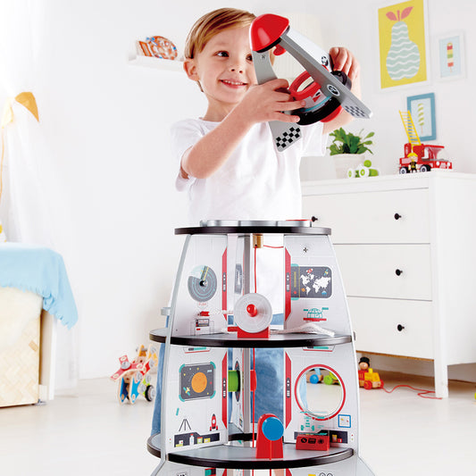 Child playing with a toy kitchen set in a room with furniture and decor.