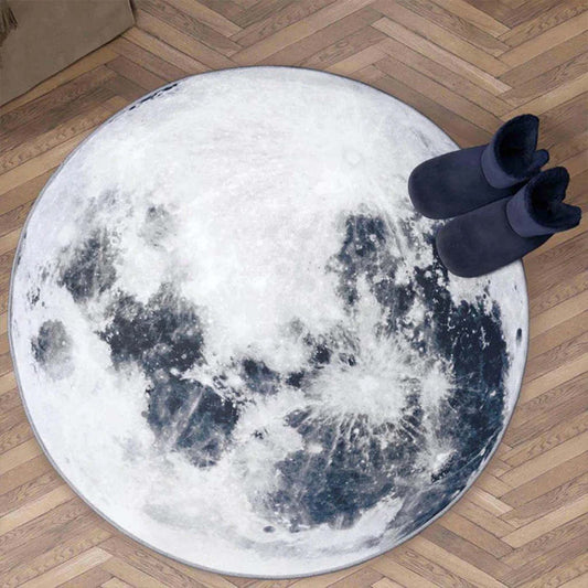 Round moon-patterned rug on a wooden floor with dark blue boots on top.