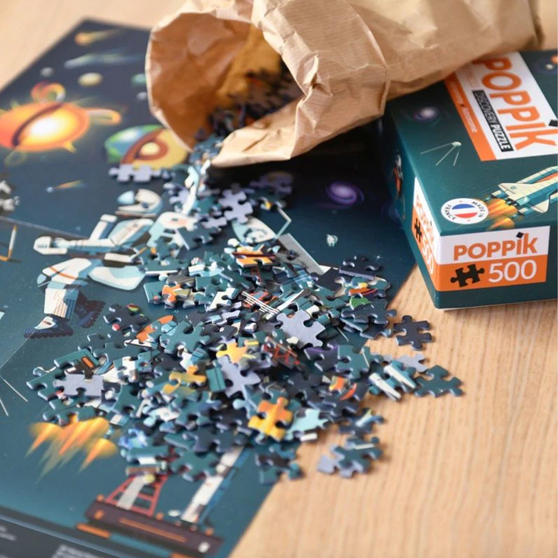 Puzzle with pieces scattered on a table, next to a PopPik box.