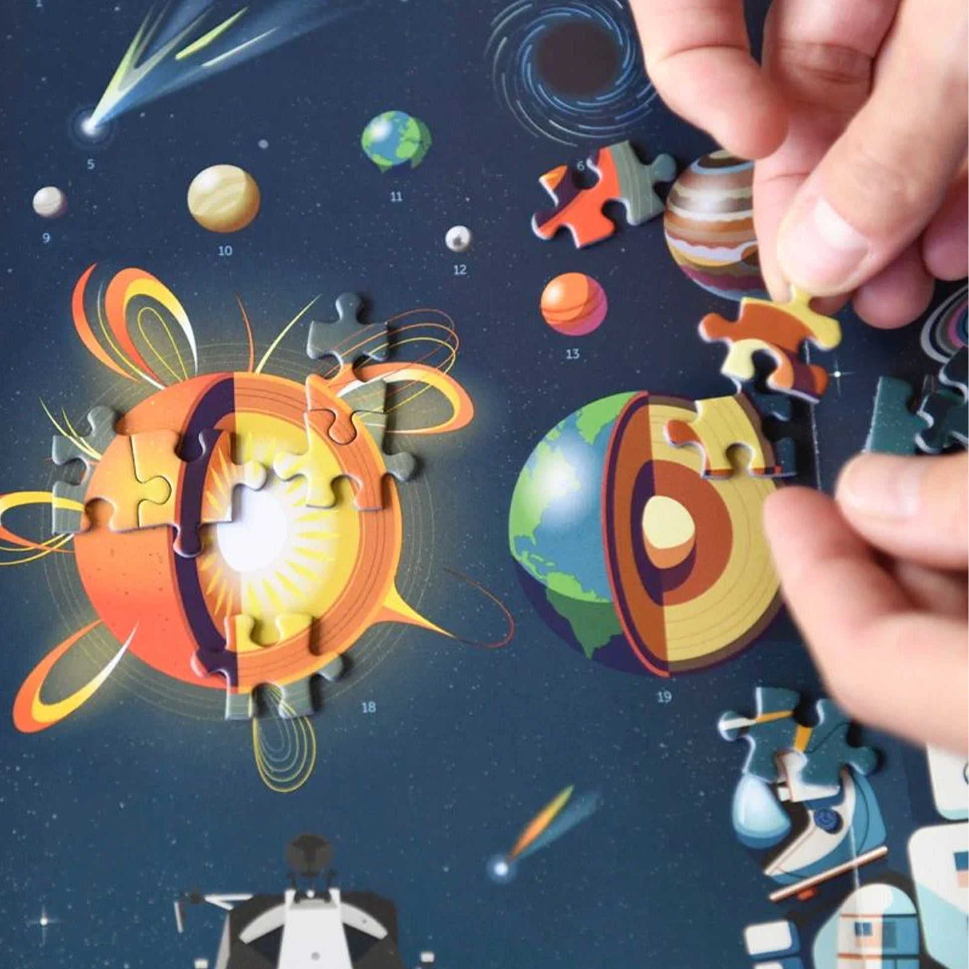 Solar system-themed puzzle with colorful planets and a hand placing a piece.