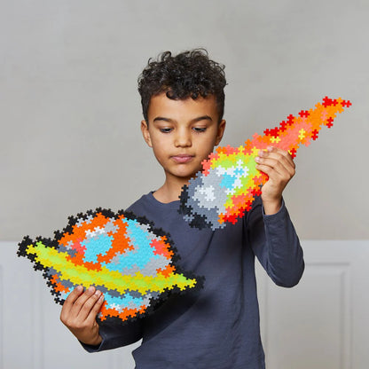 Child holding two colorful puzzle pieces shaped like planets against a plain background
