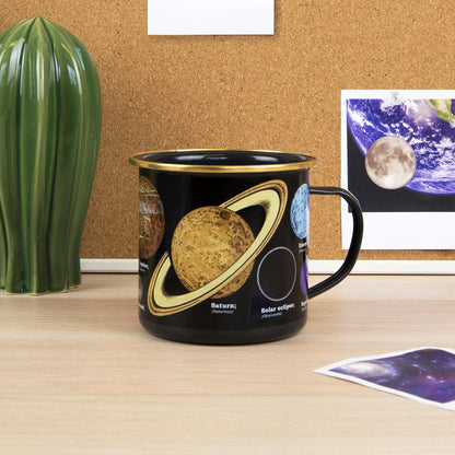 Black mug with space-themed design on a desk next to a cactus plant