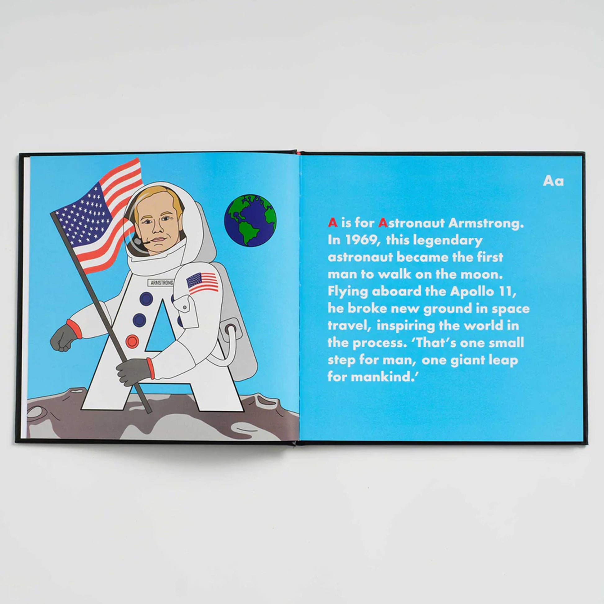 Book open to a page about Astronaut Armstrong with an illustration of an astronaut holding an American flag.