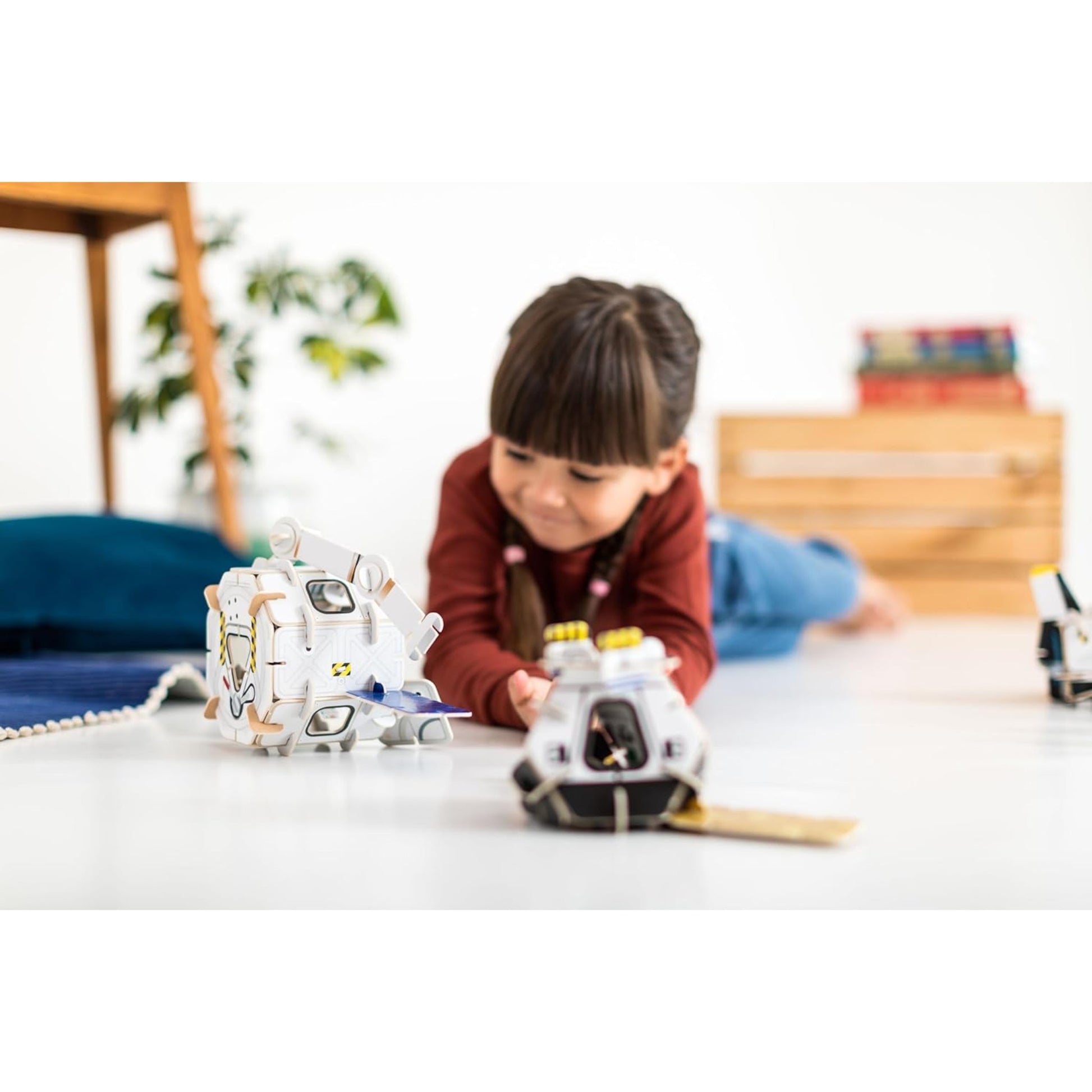 Child playing with toy robots on a white surface