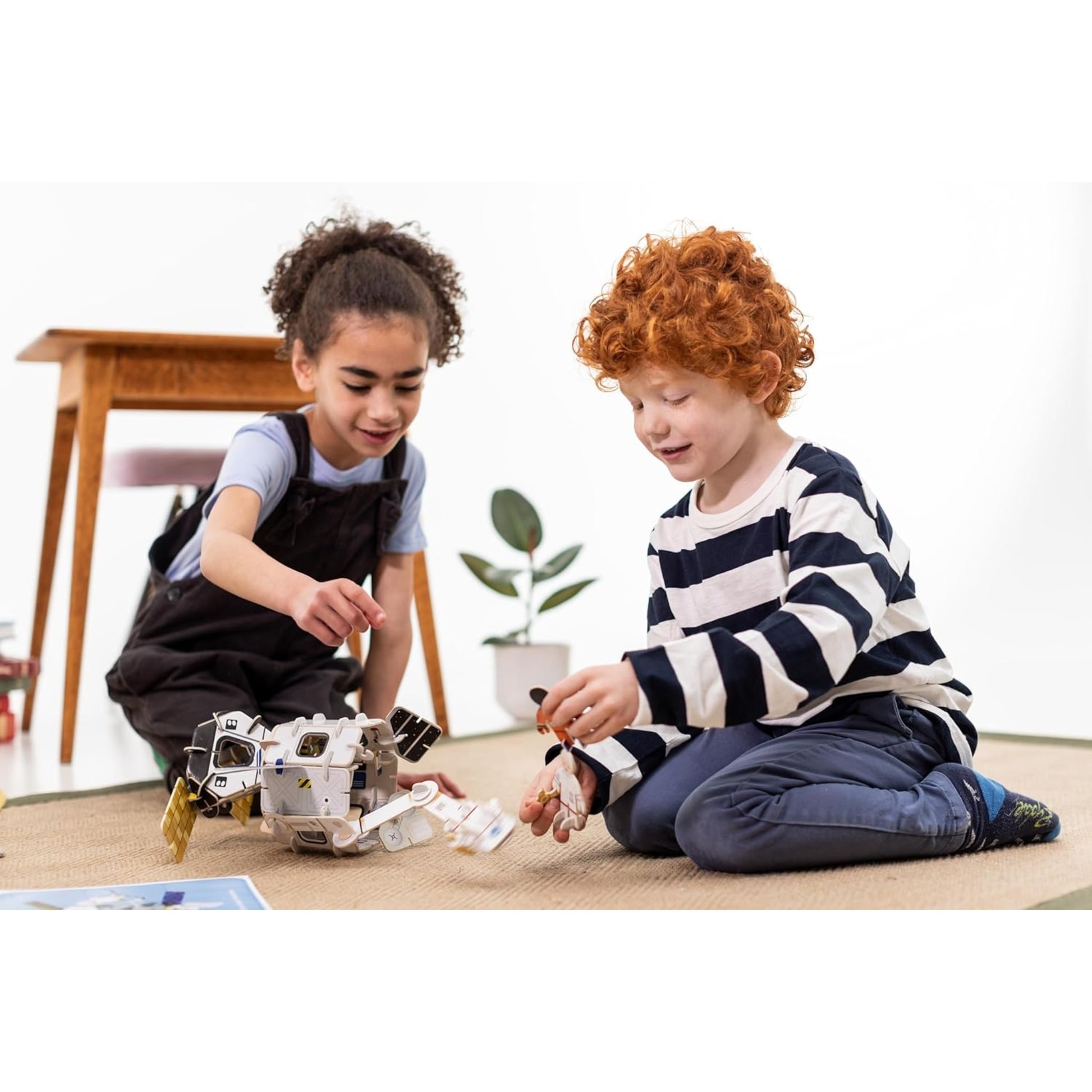 Two children playing with a robot on a carpeted floor.